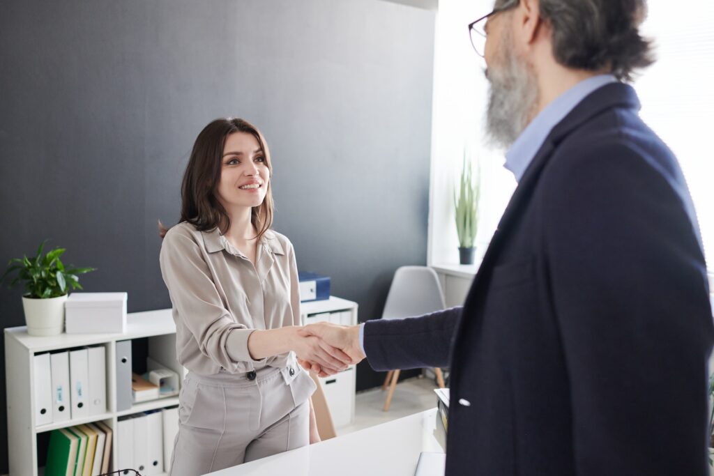 A woman welcomes a male client to her office ready to start a meeting