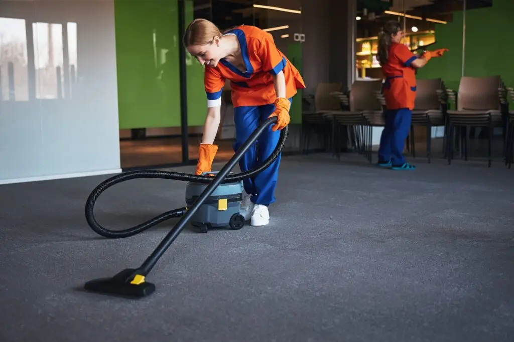 A janitor commercial cleaning team vaccuming an office space