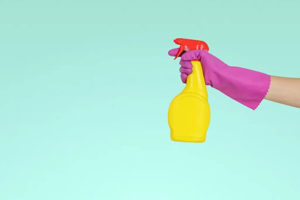 An aesthetic graphic of a gloved hand holding a yellow cleaning spray bottle