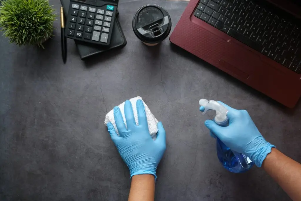 A top-down view of someone spray cleaning an office desk